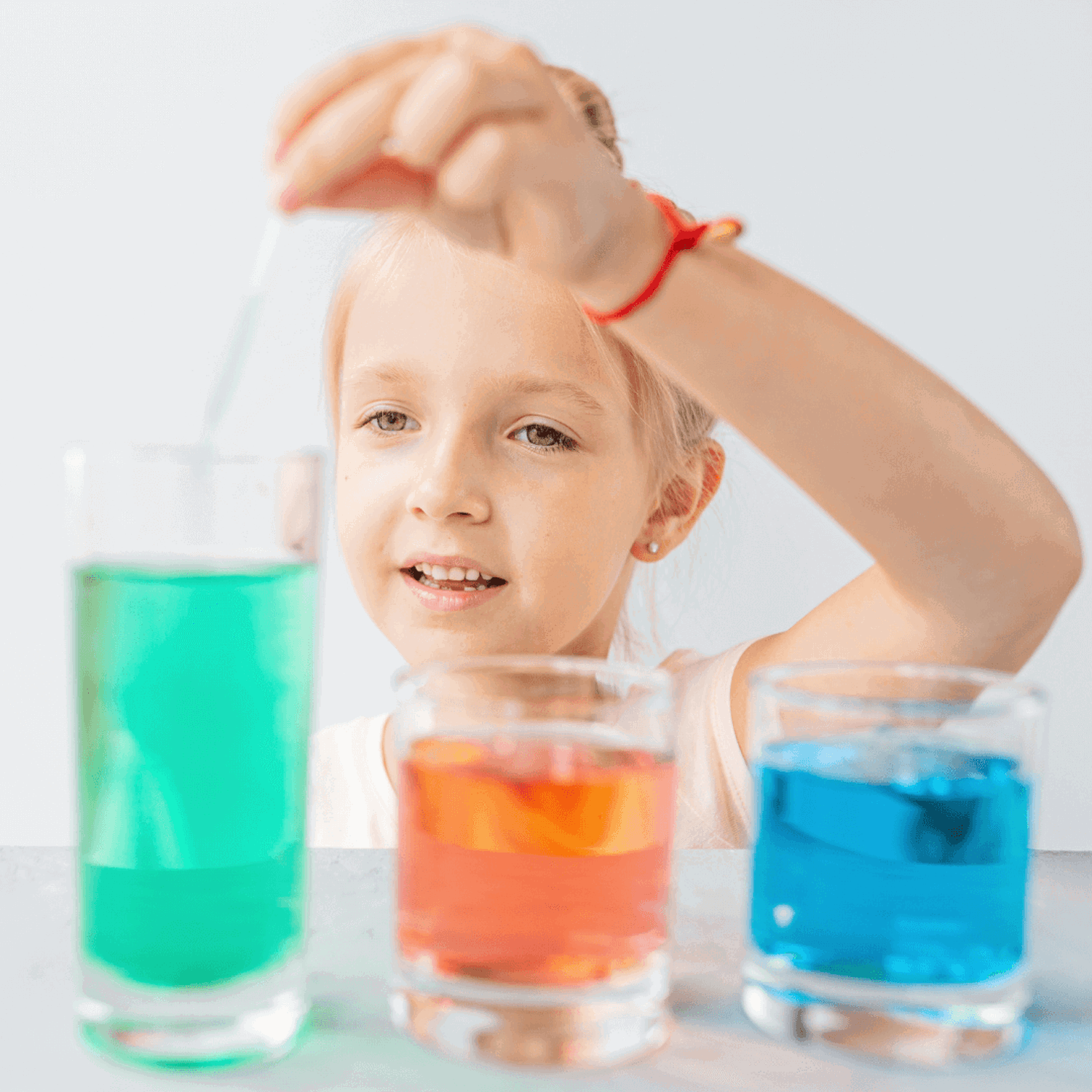 Child experimenting with coloured liquid in beakers